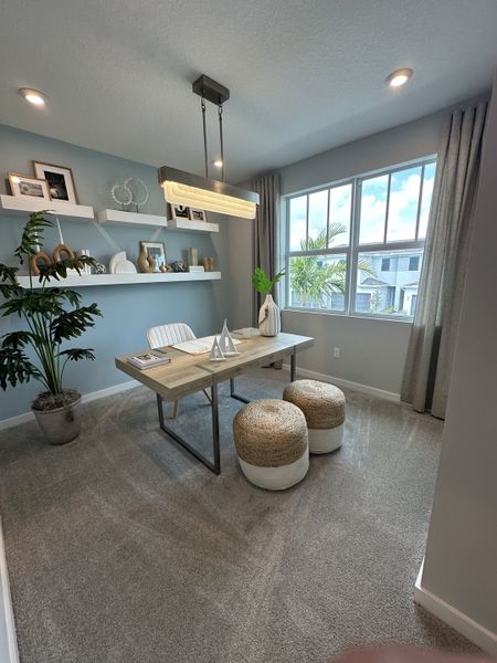 A cozy home office with a sleek desk, modern lighting, and decorative shelves, offering a serene atmosphere.