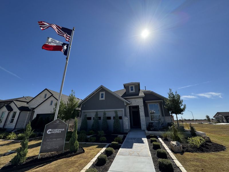 A charming home with stone accents and manicured landscaping in Nolina by Chesmar Homes (Georgetown, TX).
