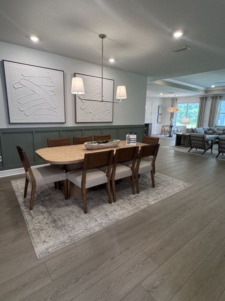 A chic dining area with a wooden table, modern art, and soft lighting, seamlessly flowing into a cozy living space.