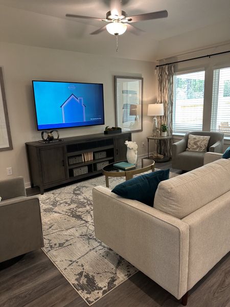 A cozy living room with a sectional sofa, elegant TV stand, abstract rug, and abundant natural light from large windows. A cozy living room with a sectional sofa, elegant TV stand, abstract rug, and abundant natural light from large windows.