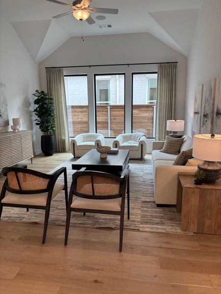 A cozy living room with elegant seating, large windows, and neutral décor, featuring soft lighting and a sleek coffee table.