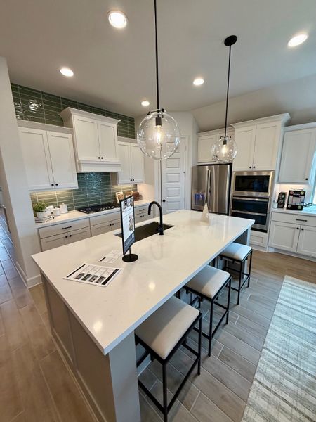 A modern kitchen with sleek white cabinets, an island with seating, and elegant pendant lights. A modern kitchen with sleek white cabinets, an island with seating, and elegant pendant lights.