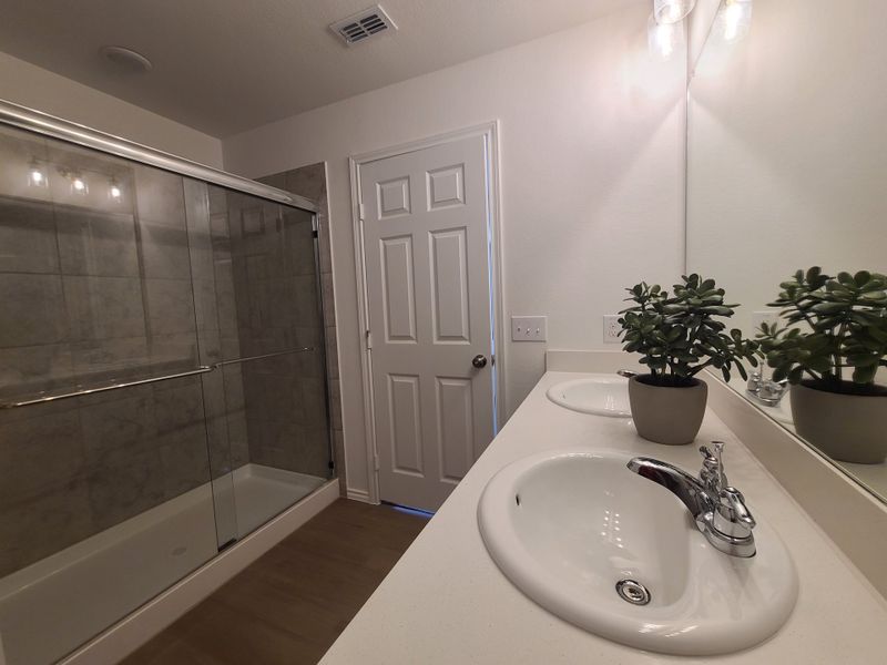 A modern bathroom with dual sinks, sleek white countertops, glass shower doors, and ambient lighting. A modern bathroom with dual sinks, sleek white countertops, glass shower doors, and ambient lighting.