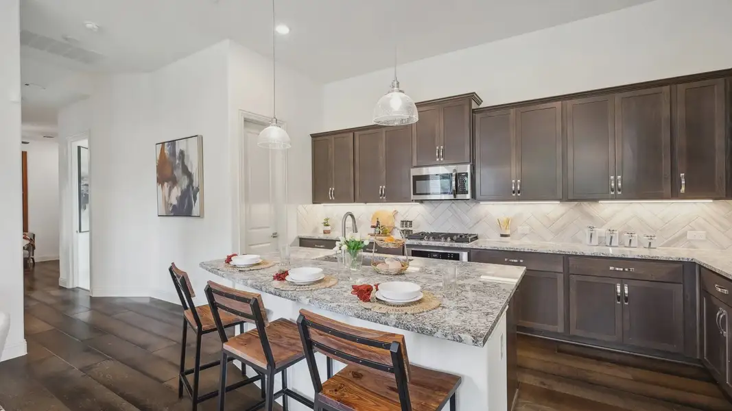 Experience luxury with granite countertops and elegant herringbone backsplash in Heritage Park's sophisticated kitchen.