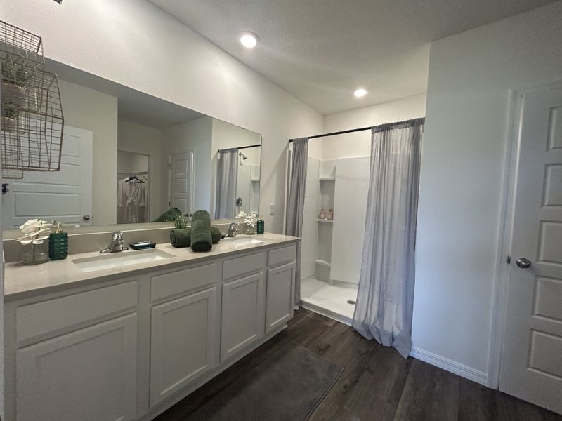 A modern bathroom with dual sinks, elegant dark flooring, and a sleek shower curtain for a stylish touch.
