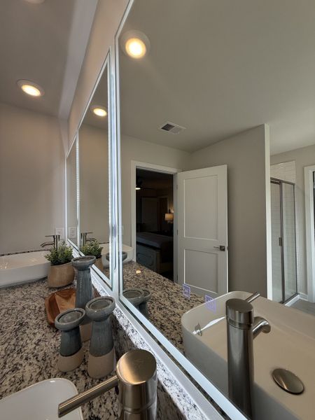 A modern bathroom featuring granite countertops, dual sinks, sleek fixtures, and ambient lighting. A modern bathroom featuring granite countertops, dual sinks, sleek fixtures, and ambient lighting.