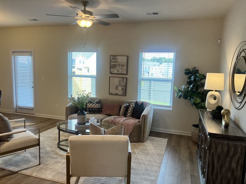 A cozy living room with modern decor, featuring neutral tones, a glass coffee table, and elegant artwork.