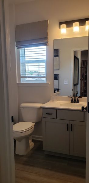 A cozy bathroom featuring a sleek vanity, elegant lighting, and a window with blinds offering natural light. A cozy bathroom featuring a sleek vanity, elegant lighting, and a window with blinds offering natural light.