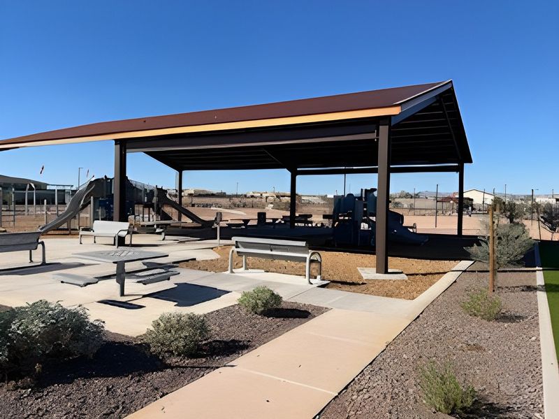 A modern outdoor pavilion with seating and a playground in North Copper Canyon by Oakwood Homes Co (Surprise, AZ).