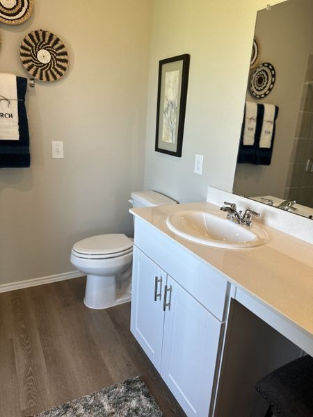 A modern bathroom with white cabinetry, sleek fixtures, and decorative wall art, creating a stylish and inviting space.