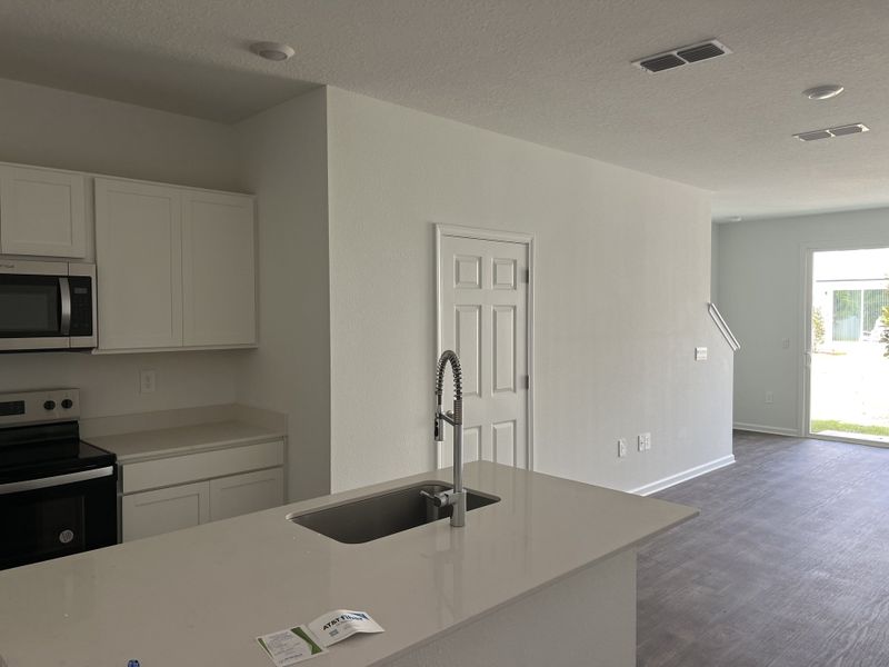 A modern kitchen with sleek white cabinetry, stainless steel appliances, and a spacious layout for seamless living. A modern kitchen with sleek white cabinetry, stainless steel appliances, and a spacious layout for seamless living.