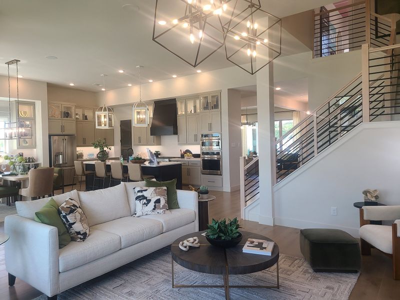 A spacious living area with modern lighting, a cozy sofa, and an open kitchen featuring sleek cabinets and a stylish staircase. A spacious living area with modern lighting, a cozy sofa, and an open kitchen featuring sleek cabinets and a stylish staircase.