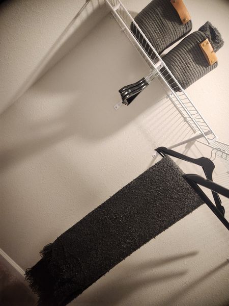 A minimalist closet space with a wire shelf, stylish baskets, and sleek hangers, offering a tidy storage solution.