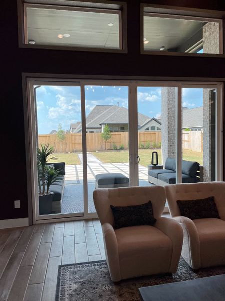 A contemporary living area with plush seating, large windows, and a view of a stylish patio.