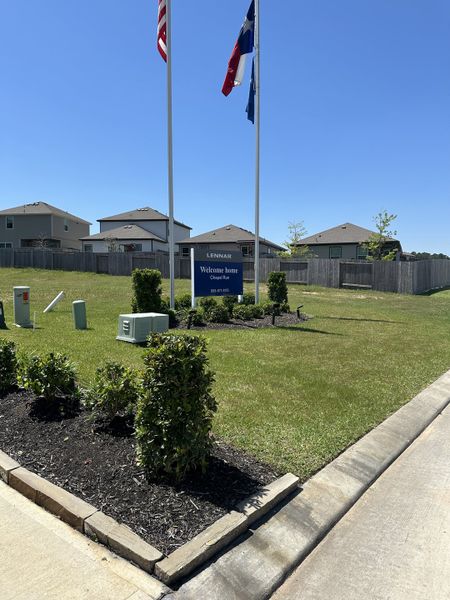 A welcoming landscaped entrance with flags in the Chapel Run community by Lennar, Montgomery, TX.