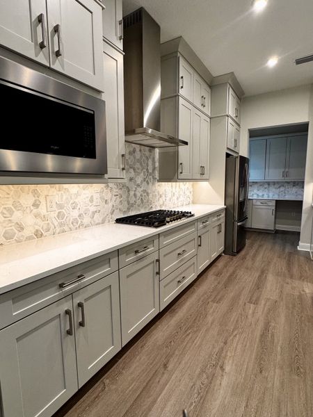 A modern kitchen featuring sleek gray cabinets, hexagonal tile backsplash, and stainless steel appliances. A modern kitchen featuring sleek gray cabinets, hexagonal tile backsplash, and stainless steel appliances.
