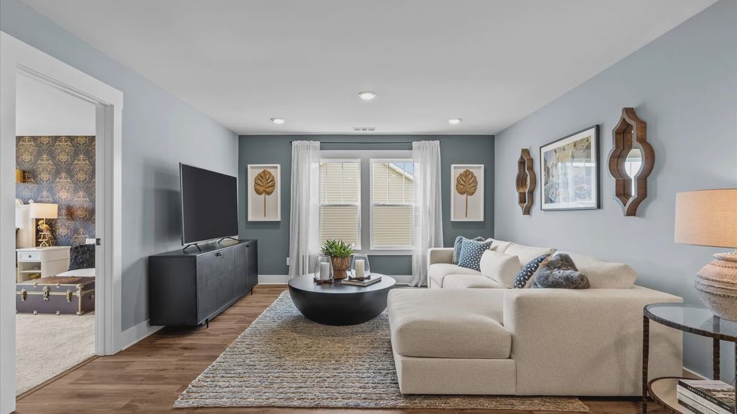 Cozy loft space with large windows and hardwood flooring in two story home at Mulberry Estates by DRB Homes
