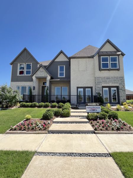 A beautiful two-story home with gray accents and lush landscaping in Polo Ridge by First Texas Homes (Forney, TX).