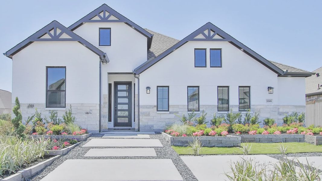 Elegant white facade with black accents, lush landscaping, and stone elements in Oakwood Estates. Elegant white facade with black accents, lush landscaping, and stone elements in Oakwood Estates.