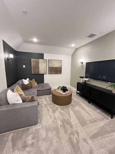 A cozy media room with a plush gray sectional, abstract art, and modern lighting. A cozy media room with a plush gray sectional, abstract art, and modern lighting.