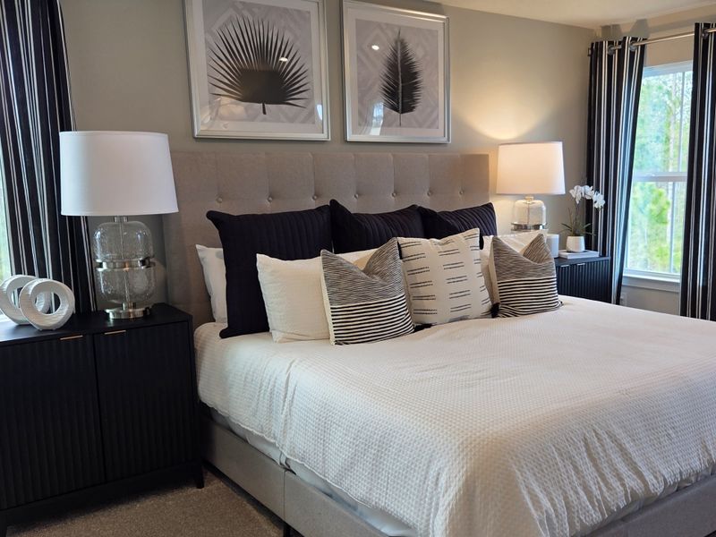 A chic bedroom with a tufted headboard, modern lamps, striped curtains, and botanical artwork. A chic bedroom with a tufted headboard, modern lamps, striped curtains, and botanical artwork.