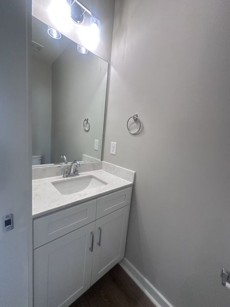 A sleek bathroom with a white vanity, marble countertop, large mirror, and modern lighting fixtures.