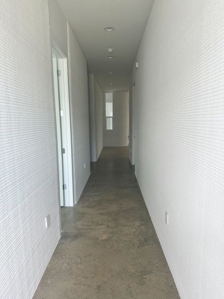 A modern hallway with textured walls, polished concrete flooring, and sleek recessed lighting.