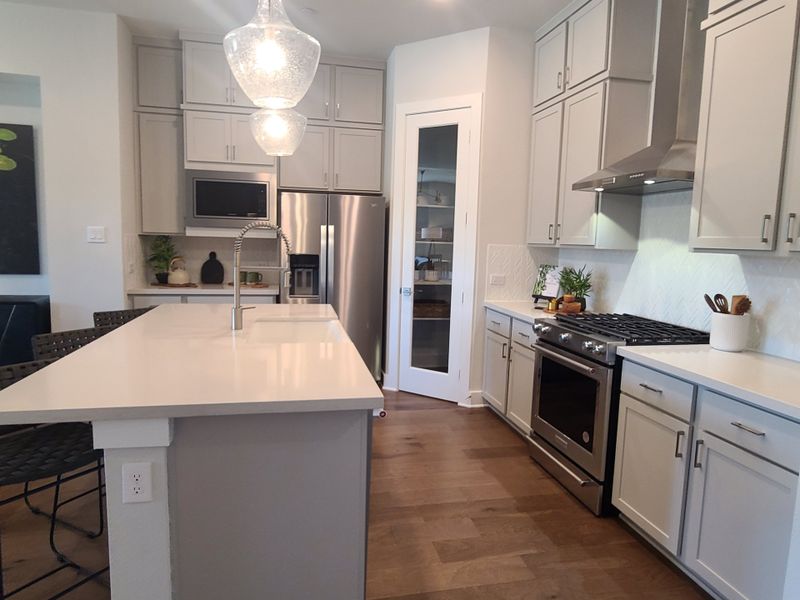 A sleek kitchen with modern cabinetry, stainless steel appliances, and a spacious island under elegant pendant lighting.