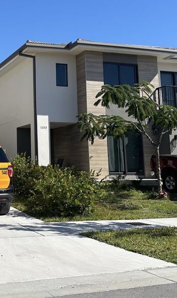 Modern home with wood accents and lush landscaping in On Alba by Onx Homes, Florida City, FL.