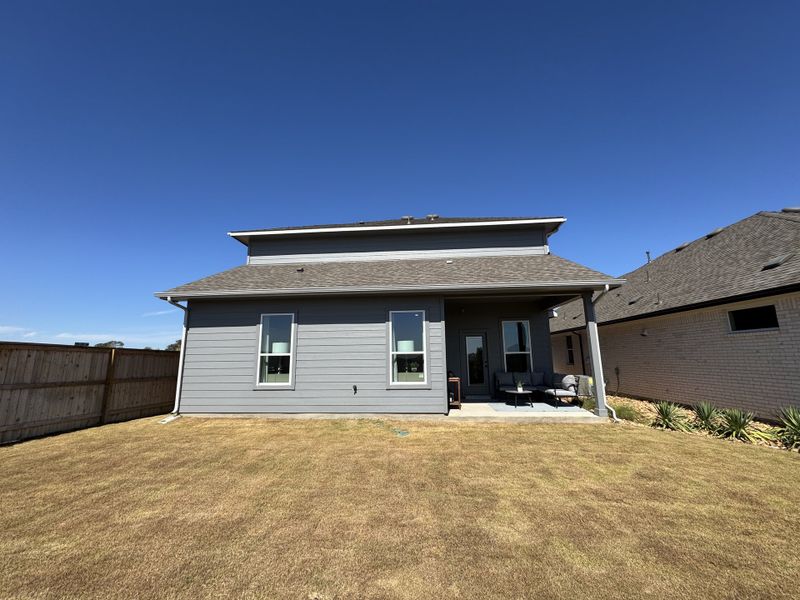 A modern gray home with a spacious yard in Nolina by Chesmar Homes (Georgetown, TX).