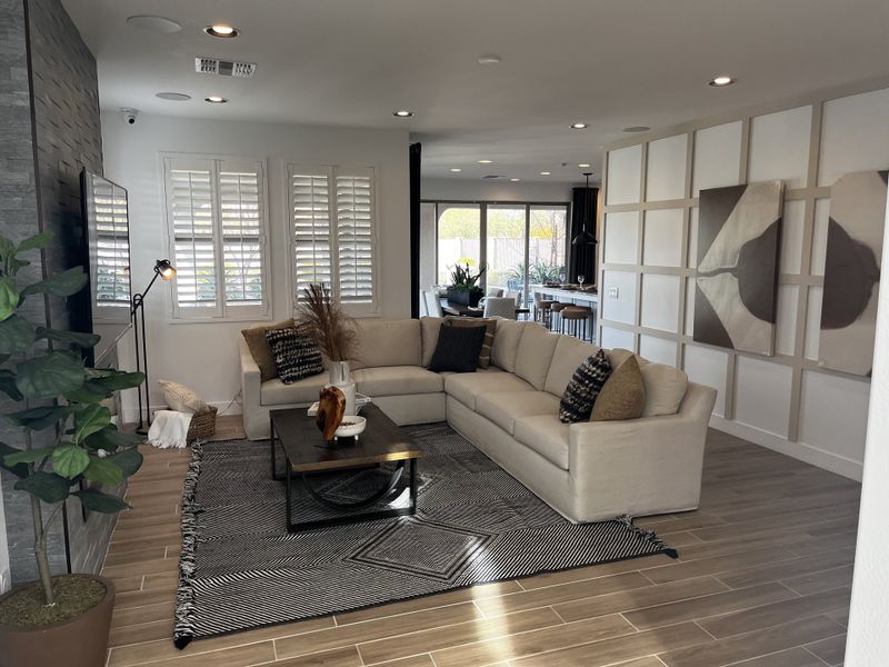 A modern living room with an L-shaped sofa, textured accent wall, and warm lighting.