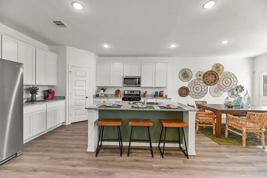 A kitchen with white cabinets and a table with plates on it. A kitchen with white cabinets and a table with plates on it.