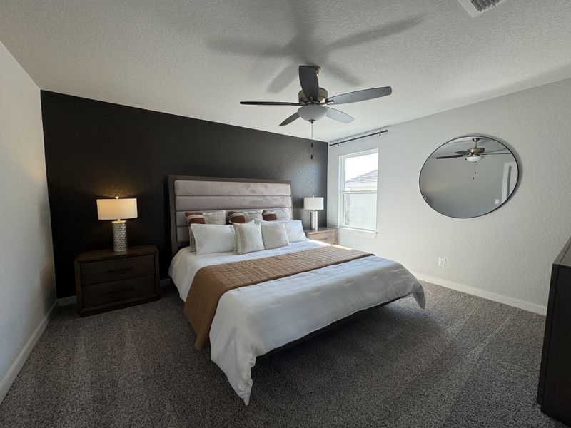 A modern bedroom with a taupe headboard, dark accent wall, and sleek round mirror for a chic and cozy ambiance. A modern bedroom with a taupe headboard, dark accent wall, and sleek round mirror for a chic and cozy ambiance.