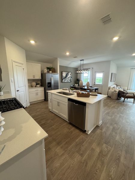 A contemporary kitchen with white cabinets, stainless steel appliances, and wood flooring, featuring a central island and open layout. A contemporary kitchen with white cabinets, stainless steel appliances, and wood flooring, featuring a central island and open layout.
