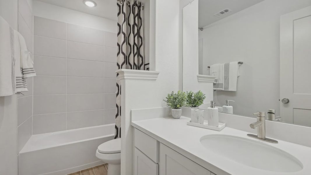 Immerse in luxury with a sleek white vanity, elegant chrome fixtures, and exquisite stone tile in Bel Air Village.