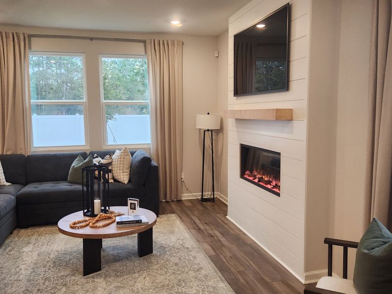 A cozy living room with a sectional sofa, electric fireplace, and modern decor, perfect for relaxation.