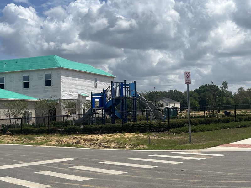 A developing home with turquoise roofing near a playground in Meadowlark Landing by Mattamy Homes (Apopka, FL).