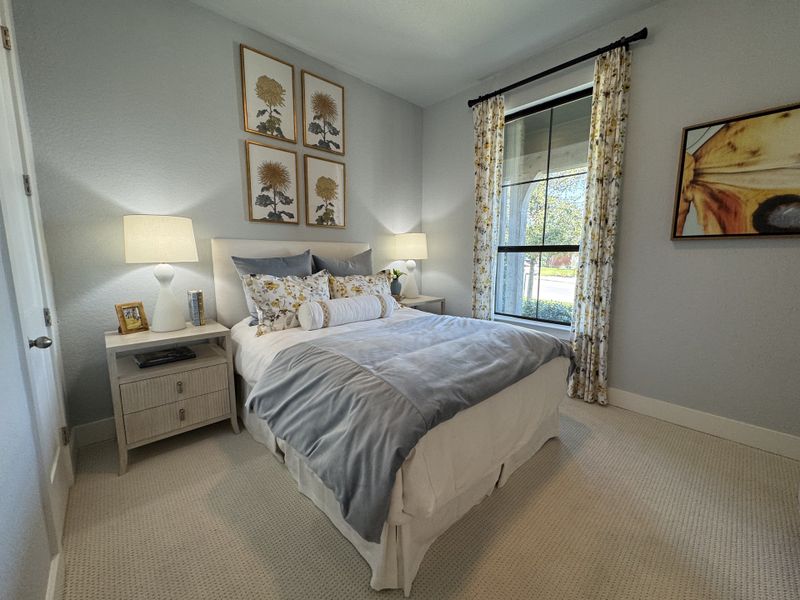 A cozy bedroom with floral accents, soft gray bedding, and elegant artwork on light blue walls. A cozy bedroom with floral accents, soft gray bedding, and elegant artwork on light blue walls.