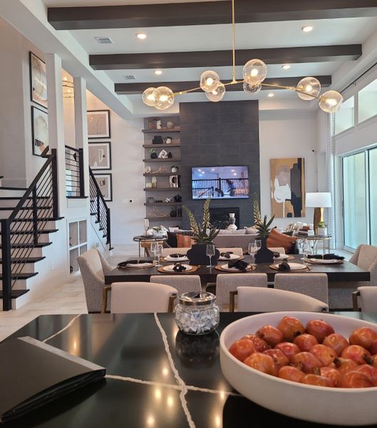 An elegant open-concept living space with modern decor, a black accent wall, and a chic dining area under stylish lighting.