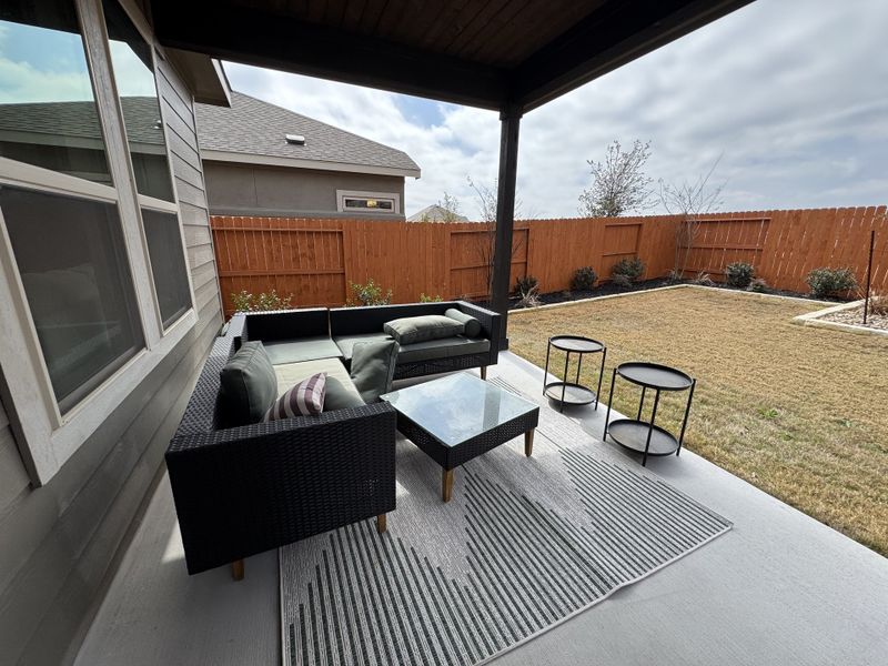 A cozy backyard patio with a modern outdoor sofa, glass table, and a well-maintained lawn. A cozy backyard patio with a modern outdoor sofa, glass table, and a well-maintained lawn.