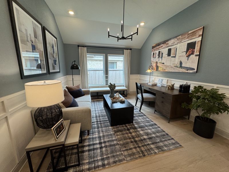 A modern living room with cozy seating, stylish wall art, and a sleek desk area.