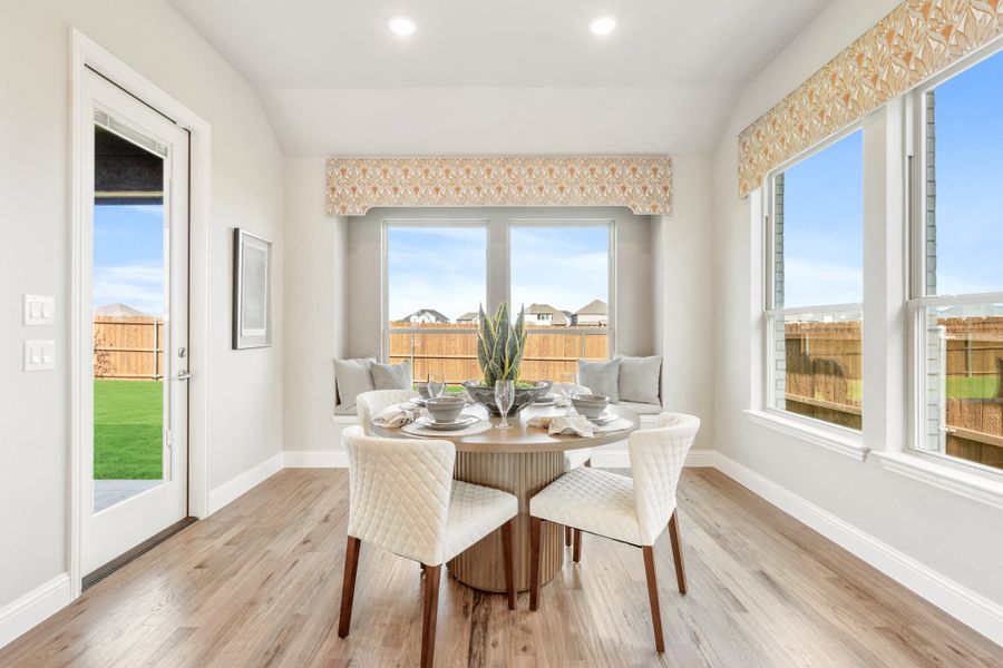 Bright breakfast nook with round dining table, window seat, and hardwood floors next to backyard door Bright breakfast nook with round dining table, window seat, and hardwood floors next to backyard door
