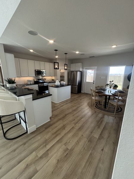 A well-designed kitchen with pendant lighting, black countertops, and a cozy breakfast nook for casual dining. A well-designed kitchen with pendant lighting, black countertops, and a cozy breakfast nook for casual dining.