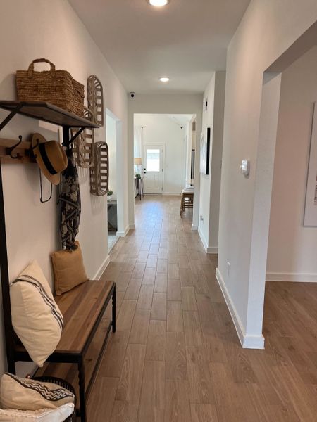 A welcoming hallway with wood flooring, tasteful decor, a cozy bench, and abundant natural light.