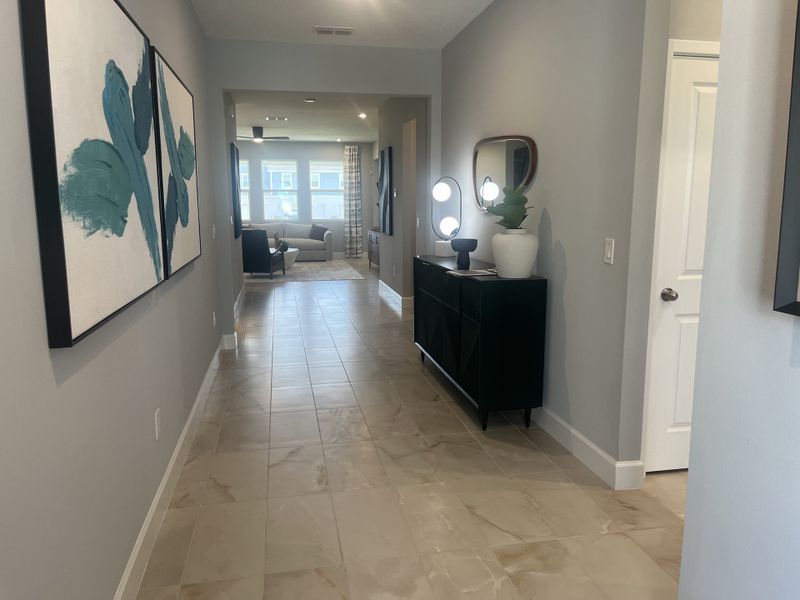 A modern hallway with abstract art, sleek console, and stylish lighting leading to a cozy living area.