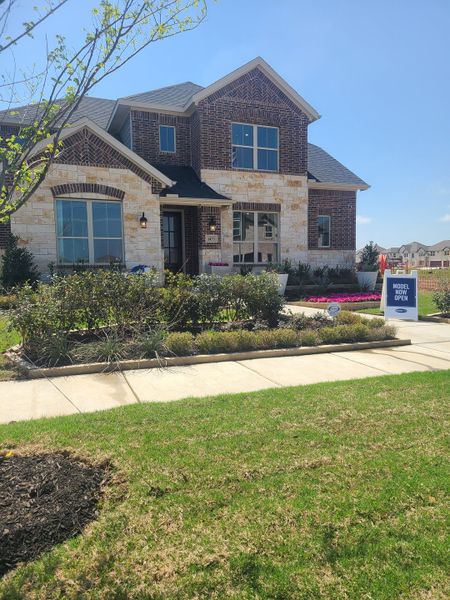 A beautiful brick and stone home with lush landscaping in Villages of Creekwood by Mattamy Homes (Frisco, TX).