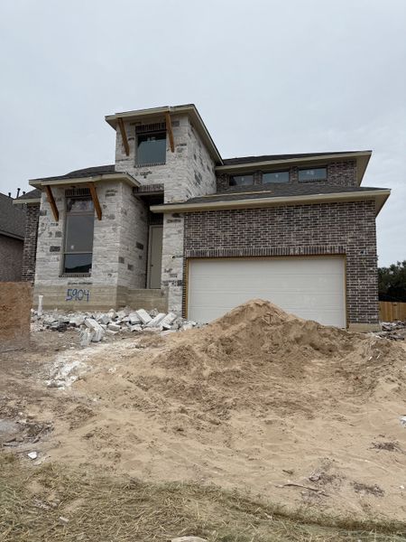 A modern stone and brick home under construction in Parkside Peninsula 50' by Perry Homes (Georgetown, TX).