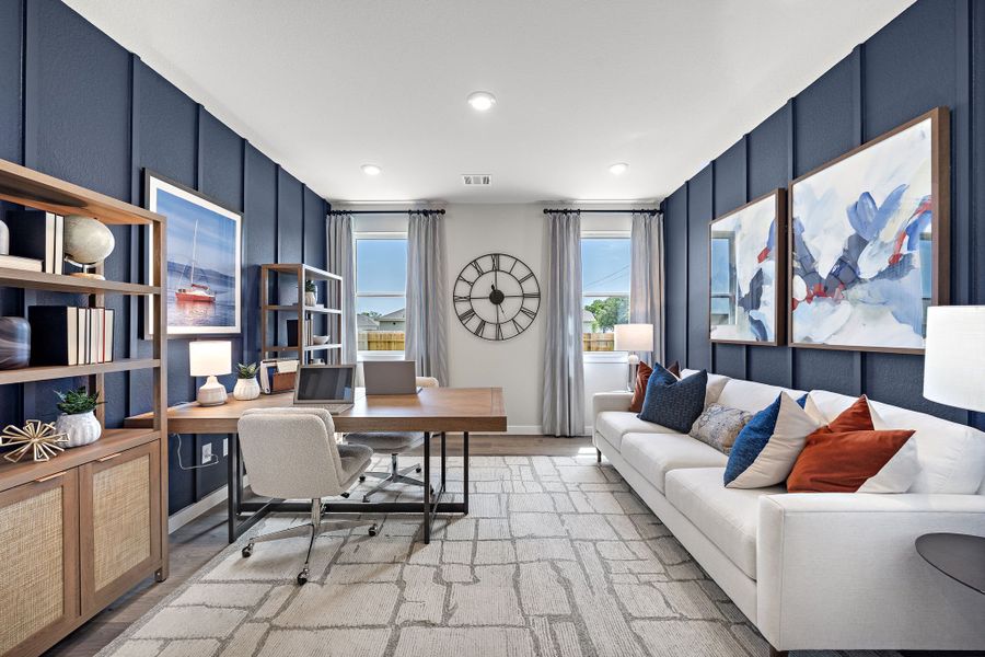 A living room with a desk and a couch.