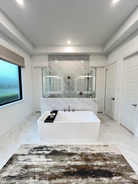 A luxurious bathroom with a freestanding tub, glass shower, and sleek marble tiling, exuding modern elegance.