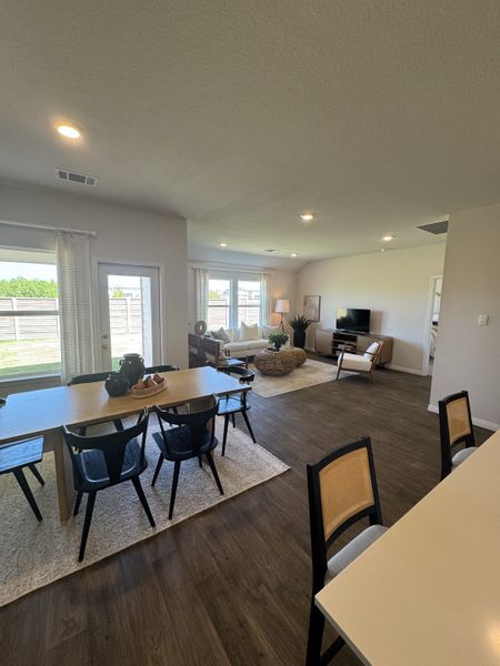 An open-concept living area with sleek wood flooring, modern dining set, and ample natural light.